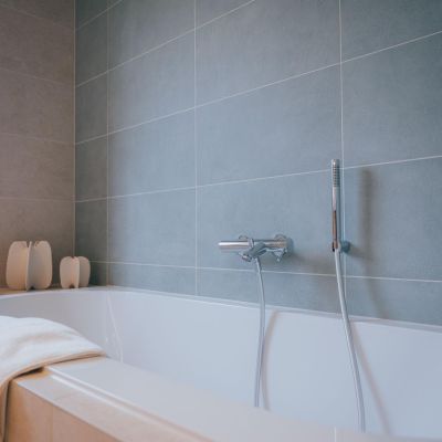 baignoire avec des faïences murales bleues verts qui donnent une impression de nature et d'extérieur